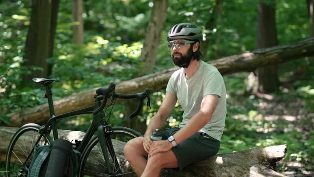 Cyclist in helmet drinks water from bottle after bike ride	