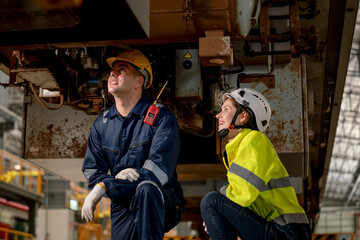 Technician man and train factory worker woman check and fix the problem and stay under electric...