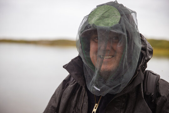 Man in Alaska wearing a mosquito net over his face to keep the bugs away