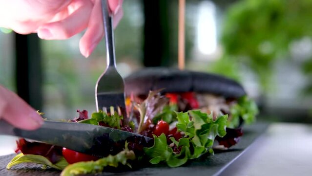 Italian style meat sandwich and salad on plate in restaurant. Man eats salad with fork, tilt up shot slow motion. High quality 4k footage