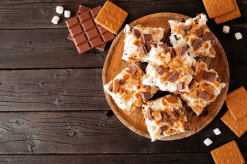 Smores brownies dessert platter. Overhead view table scene on a dark wood background.
