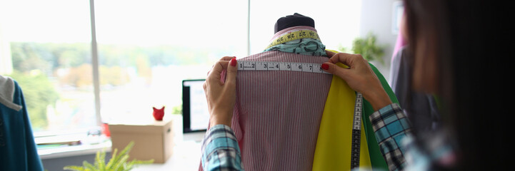 Woman fashion designer seamstress stylist measuring mannequin with tape. Working with mannequin in...