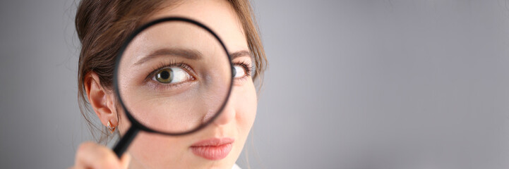 Inquisitive young woman looking through magnifying glass. Search for business ideas and new...