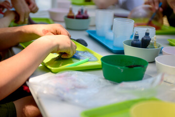 A young hand draws clear mucus from a cup. Chemical experiments.