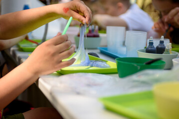 A young hand draws clear mucus from a cup. Chemical experiments.