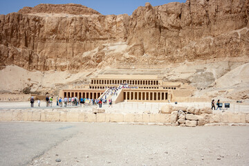 templo egipcio bajo la montaña con turistas visitándolo