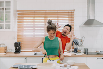 Asian couple, husband feels worry behind his wife while she is cooking for him.