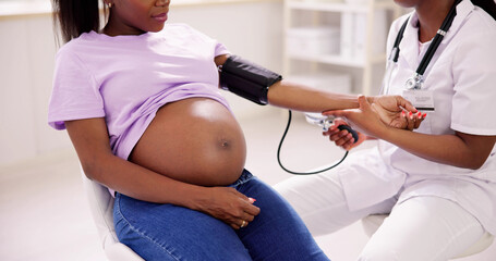 Female Doctor Measuring Blood Pressure Of Pregnant Woman