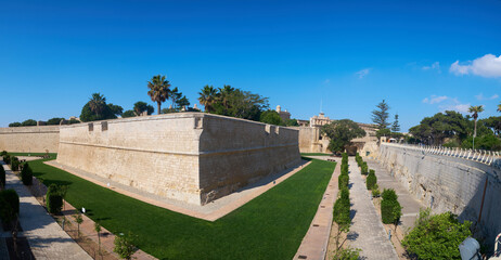 Fototapeta na wymiar Ancient hilltop fortified capital city of Malta, The Silent City, Mdina or L-Imdina, skyline against blue Spring skies with huge walls, cathedral domes and towers, fields of spring flowers