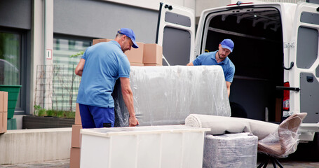 Male Workers In Blue Uniform Unloading Furniture