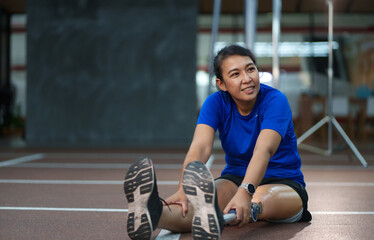 Athlete using a prosthetic leg warming up at the Gym. Woman relaxing and streching while using...
