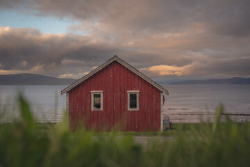 Obraz premium Red cottage of the Norwegian culture and architecture in Norway, with dynamic sunset sky