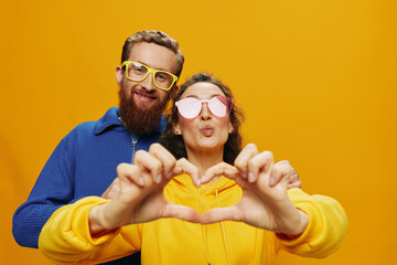 Man and woman couple smiling cheerfully and crooked with glasses, on yellow background, symbols signs and hand gestures, family shoot, newlyweds.