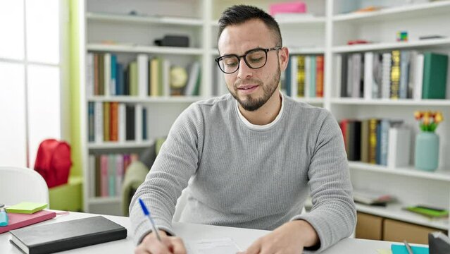Hispanic man student speaking at the camera holding pen at library university