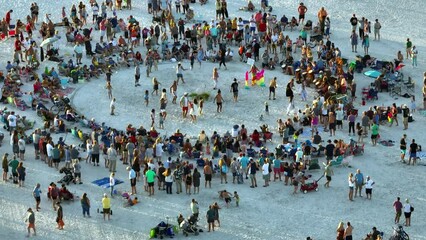 Large group of people gathered in a circle dancing and having fun on sandy beach at sea shore during summer vacations. Outdoor activities during travel time - Powered by Adobe