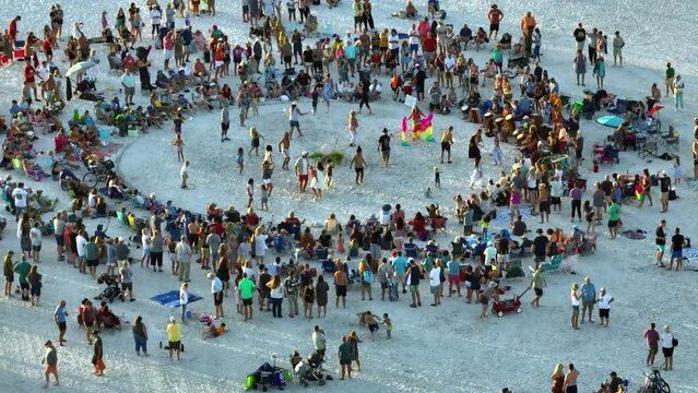Large group of people gathered in a circle dancing and having fun on sandy beach at sea shore during summer vacations. Outdoor activities during travel time