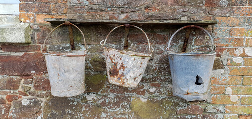 Three old fashioned metal buckets hanging in a row
