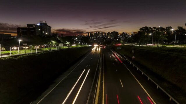 Trail of light caused by vehicular traffic in Highway with buildings from downtown in the background, in Marília,