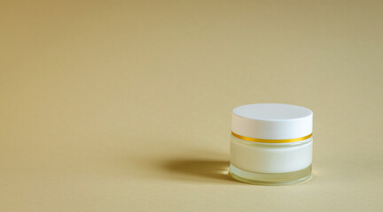 Round glass jar with face cream on a beige background. Body care concept.