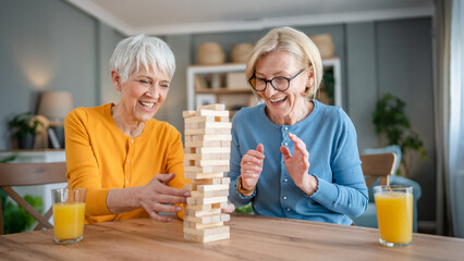 two senior women friends or sisters play leisure board game at home © Miljan Živković