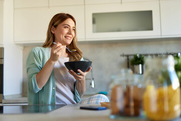 Portrait of a woman eating breakfast in the kitchen at home