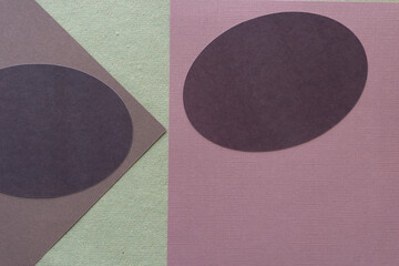 two brown machine cut oval shapes on neutral scrapbook paper sheets on green