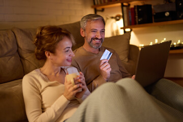 Mature couple doing online shopping using laptop and credit card at home