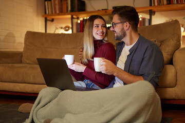 Young couple spending evening at home using laptop