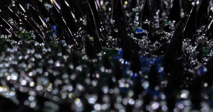 Ferrofluid tinted with colored paints. The surface of the black, blue liquid. Abstract background. A natural phenomenon of magnetism ferro fluidic substances under the action of a neodymium magnet