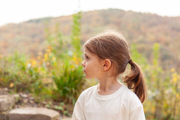 Obraz premium Portrait of a little girl in a white T-shirt on a background of autumn nature