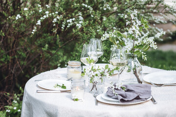Rustic elegant eco friendly zero waste trendy wedding reception table decor with fresh spring apple cherry flowers in bloom. Beautiful marriage decoration, holiday event outdoors in the family garden