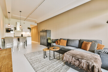a living room with couch, coffee table and kitchen in the back wall is painted white on the right side