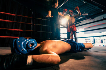 Boxing referee intervene, halting the fight to check fallen competitor after knock out. Referee...