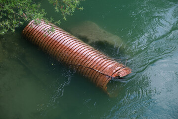Environmental pollution . Plastic tube in the river