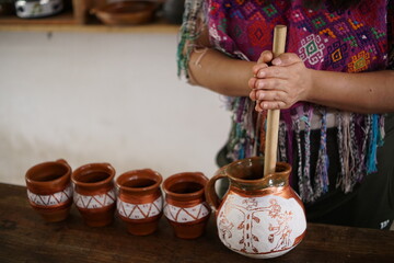 Guatemalan mayan woman making hot chocolate with molinillo blending stick