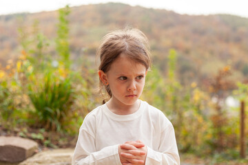 Little girl in a white T-shirt on the background of the autumn landscape