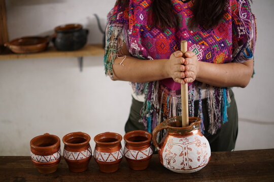 Guatemalan mayan woman making hot chocolate with molinillo blending stick