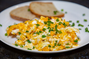 Scrambled eggs with herbs on homemade crispy wheat and rye bread in selective focus