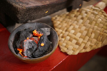 Hot burning charcoal to heat mayan grinding stone called metate