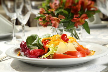 Tropical salad with lettuce, tomatoes, cheese, strawberries and thinly sliced carrots