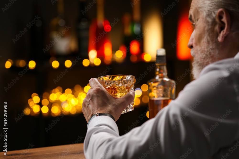 Wall mural Senior man with glass of whiskey at bar counter, closeup. Space for text