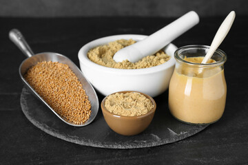 Aromatic mustard powder and seeds on black table