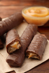Sweet tasty chocolate bars with caramel on wooden table, closeup