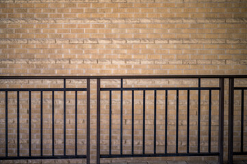 Black Metal Railing with a Tan Brick Wall Background.