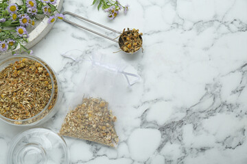 Scented sachet and dried chamomile flowers on white marble table, flat lay. Space for text