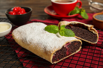 Delicious strudel with cherries and poppy seeds on table, closeup