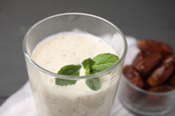 Glass of delicious date smoothie with mint on table, closeup