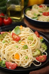 Plate of delicious pasta primavera and ingredients on table, closeup