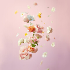 Beautiful spring flowers flying in the air, against pink background; Creative spring floral layout. Minimal birthday, valentines or wedding concept. AI generated