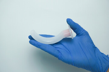 Medical worker wearing medical gloves holding an OPA (Oropharyngeal airway) is a medical device...